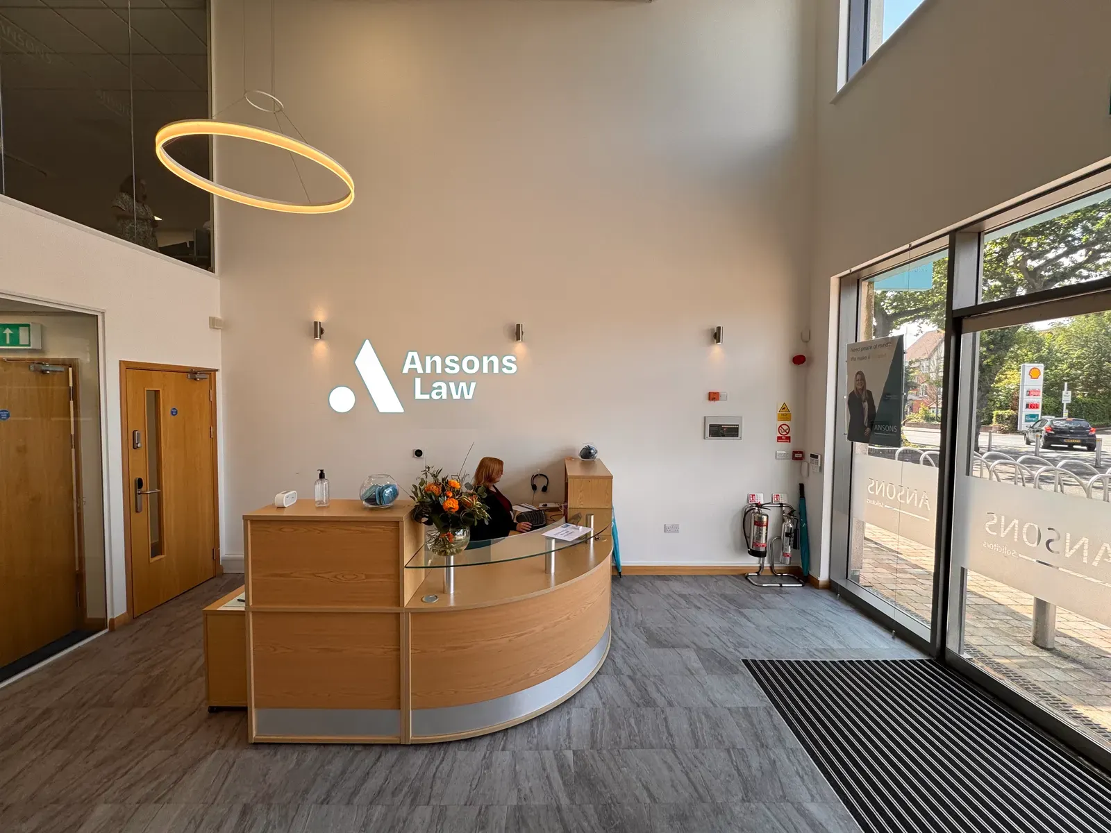 Ansons Law reception desk with the teal Ansons Law logo lit on the wall behind it.