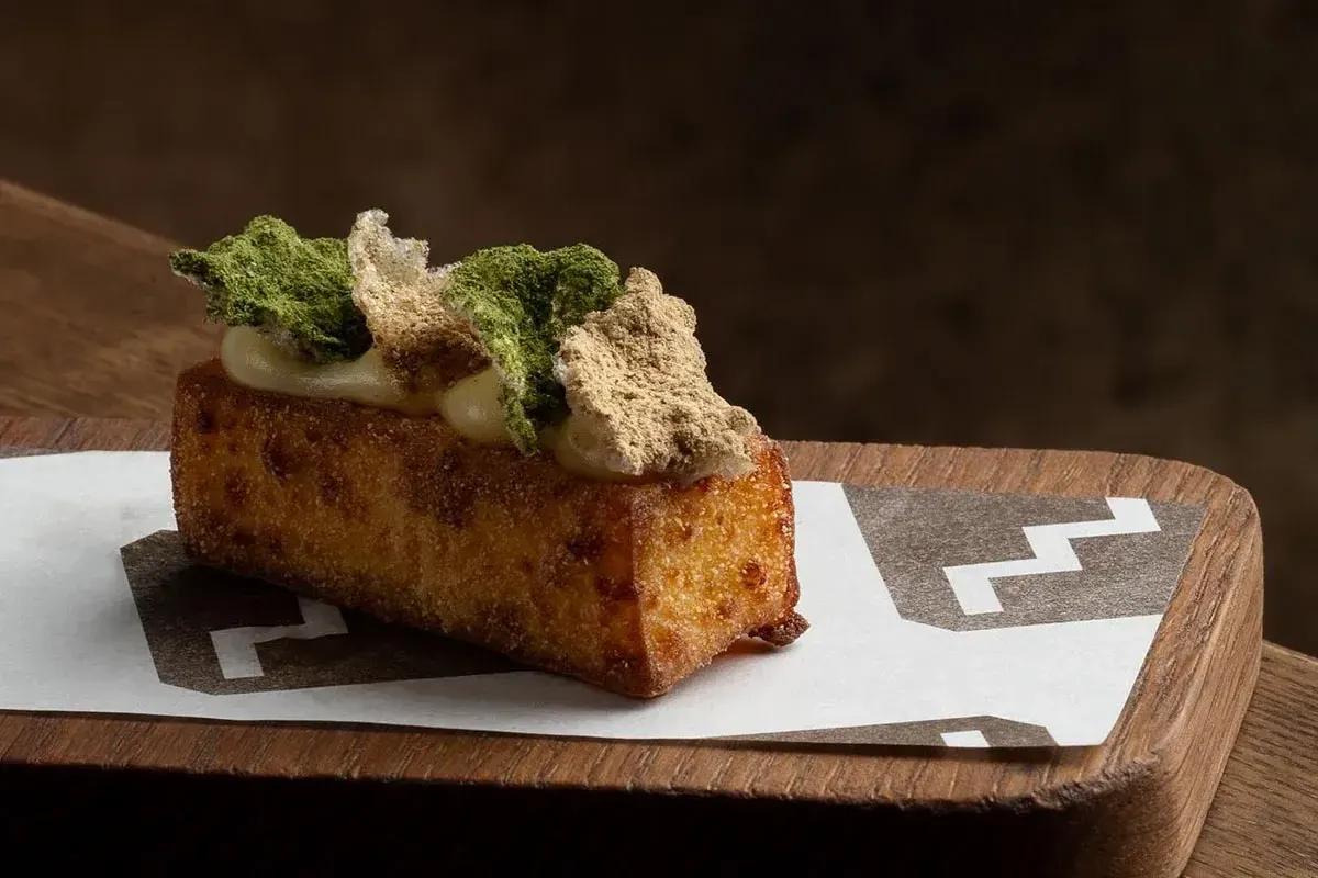 A dish on a wooden board, set on paper printed with the Upstairs stepped pattern.